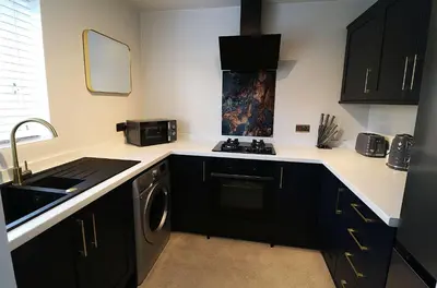 a kitchen with black cabinets and a sink and a stove at Lancaster 2 Bedroom House - Driveway Parking in Lancaster