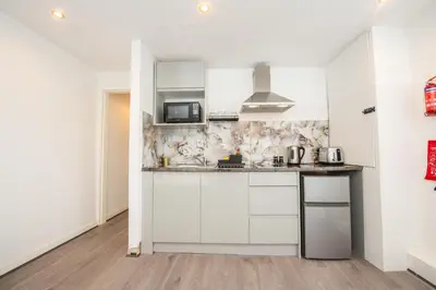 a kitchen with white cabinets and a microwave at The Moscow Studios in Liverpool