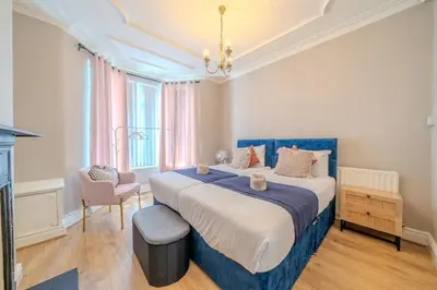a large bedroom with a blue bed and a chair at Sleeps 7- Spacious 3 Bed House w Free Parking in Liverpool
