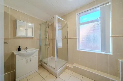 a bathroom with a shower and a sink and a window at Sleeps 7- Spacious 3 Bed House w Free Parking in Liverpool