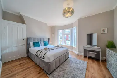 a bedroom with a large bed and a television at Sleeps 7- Spacious 3 Bed House w Free Parking in Liverpool