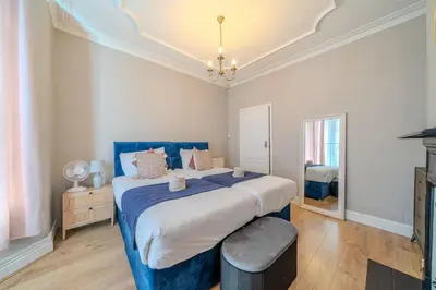 a bedroom with a large bed with a blue blanket at Sleeps 7- Spacious 3 Bed House w Free Parking in Liverpool