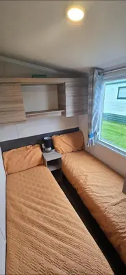 two beds in a small room with a window at Ocean Edge 13 in Heysham