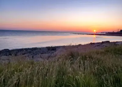 a sunset over a beach with the ocean at Ocean Edge 13 in Heysham