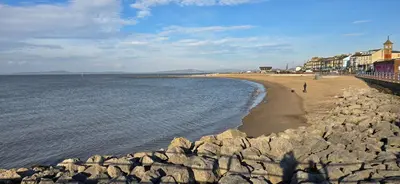a beach with rocks and a person walking on the beach at Ocean Edge 13 in Heysham
