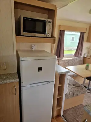 a small kitchen with a refrigerator and a microwave at 6 Berth Holiday home near the beach in Morecambe