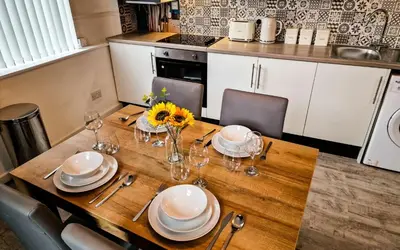 a wooden table with plates and glasses on it at Lodginet Stays - County Luxe - 2BR Flat 1 in Liverpool