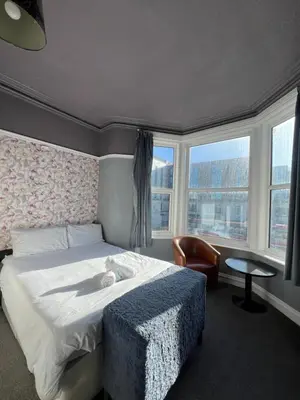 a bedroom with a bed and a chair and windows at No1 Lord street in Blackpool
