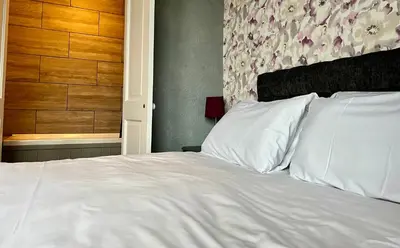 a bedroom with a white bed with a floral wall at No1 Lord street in Blackpool