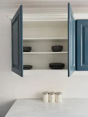 a kitchen with blue cabinets with plates and bowls at Breck House, 10 Mins to City Centre 5 Min Walk to Anfield Stadium in Liverpool