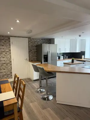 a kitchen with white cabinets and a table and chairs at Apartment 15 mins to Lake District & BAE Systems in Dalton in Furness