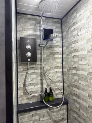 a shower with a hose attached to a brick wall at Apartment 15 mins to Lake District & BAE Systems in Dalton in Furness