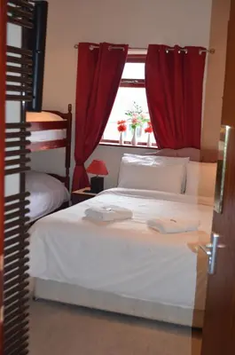 a bedroom with two beds with red curtains and a window at Lyndhurst Hotel in Blackpool