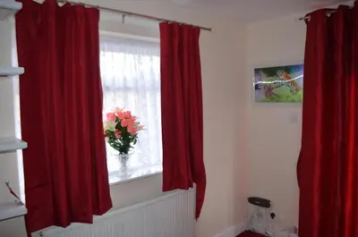 a window with red curtains and a vase with flowers in it at Lyndhurst Hotel in Blackpool