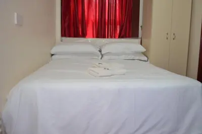 a white towel sitting on a white bed with a red window at Lyndhurst Hotel in Blackpool