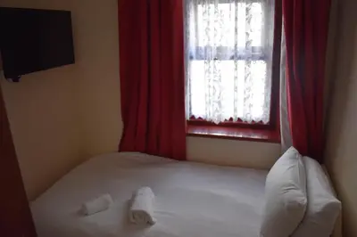 a bedroom with a bed and a window with red curtains at Lyndhurst Hotel in Blackpool