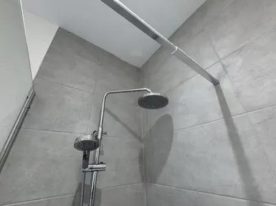 a shower with a shower head in a bathroom at Beach Apartments in Cleveleys