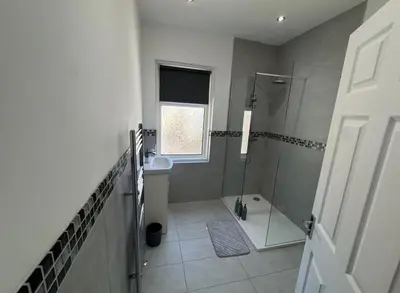 a bathroom with a shower and a toilet and a window at Beach Apartments in Cleveleys