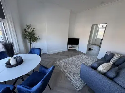 a living room with a white table and blue chairs at Beach Apartments in Cleveleys