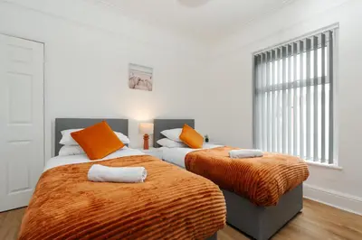 two beds in a white room with orange pillows at 4 Bed near Anfield Stadium-Perfect for Groups & Contractors in Liverpool