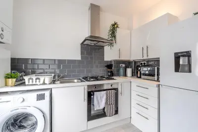 a white kitchen with a washer and dryer at 4 Bed near Anfield Stadium-Perfect for Groups & Contractors in Liverpool
