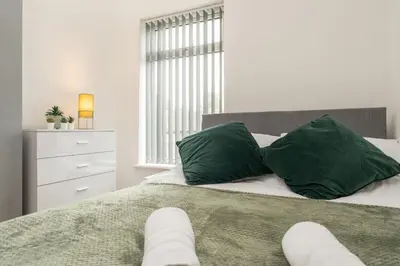 a white bedroom with a bed with green pillows at 4 Bed near Anfield Stadium-Perfect for Groups & Contractors in Liverpool