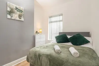 a bedroom with a bed with two green pillows at 4 Bed near Anfield Stadium-Perfect for Groups & Contractors in Liverpool