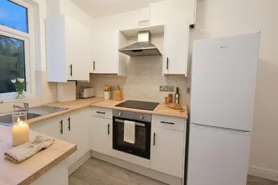 a kitchen with white cabinets and a refrigerator at New Stylish Modern Home & Free Parking! in Darwen