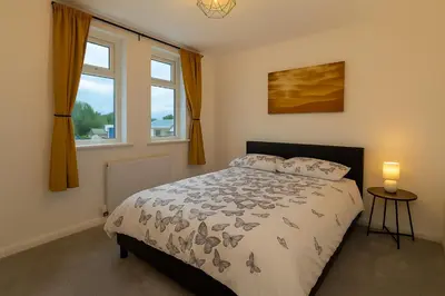 a bedroom with a bed and two windows at New Stylish Modern Home & Free Parking! in Darwen