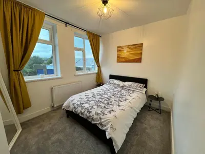 a bedroom with a bed and two windows at New Stylish Modern Home & Free Parking! in Darwen