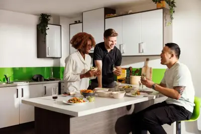 a group of people standing around a table in a kitchen at Student Only Ensuite at Prospect Point Liverpool in Liverpool