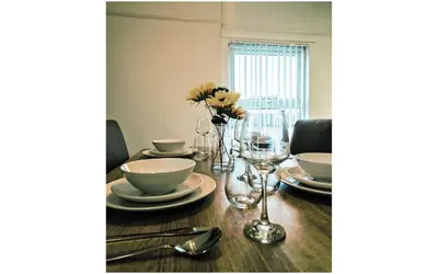 a dining room table with plates and a vase of flowers at Lodginet Stays - County Heights - 2BR Flat 3 in Liverpool