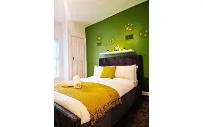 a bedroom with green walls and a bed with a yellow blanket at Lodginet Stays - County Heights - 2BR Flat 3 in Liverpool