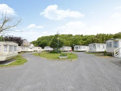 a gravel road in front of a group of mobile homes at Coastal Comfort in Millom