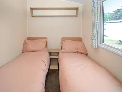 two beds in a small room with a window at Coastal Comfort in Millom