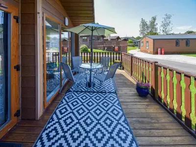 a patio with a table and an umbrella on a porch at Sunnybank in Warton