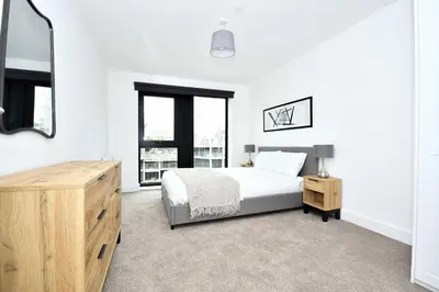 a bedroom with a bed and a dresser and a mirror at Bright Spacious 2 Bedroom Apartment in Liverpool in Liverpool