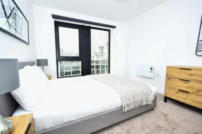 a white bedroom with a bed and a window at Bright Spacious 2 Bedroom Apartment in Liverpool in Liverpool