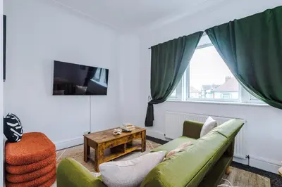 a living room with a green couch and a window at 2 Bed Apartment ,Sea Views in Blackpool