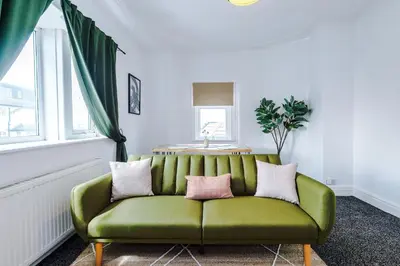 a green couch in a living room with a window at 2 Bed Apartment ,Sea Views in Blackpool