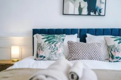 a bed with a blue headboard and pillows at 2 Bed apartment, sleeps up to 5 in Blackpool