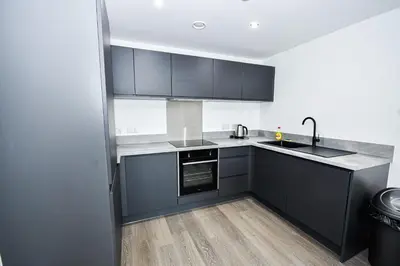 a kitchen with black cabinets and a sink at Modern & Convenient 2 Bedroom Liverpool Apartment in Liverpool