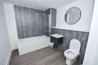 a bathroom with a tub and a toilet and a mirror at Modern & Convenient 2 Bedroom Liverpool Apartment in Liverpool