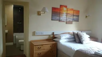 a bedroom with a bed and a bathroom with a sink at The Silverdale Hotel in Silverdale
