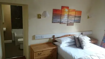 a bedroom with a bed and a toilet and paintings on the wall at The Silverdale Hotel in Silverdale