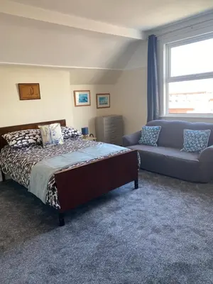 a bedroom with a bed and a couch and a window at Superior, spacious apartment in New Brighton, near Liverpool in New Brighton