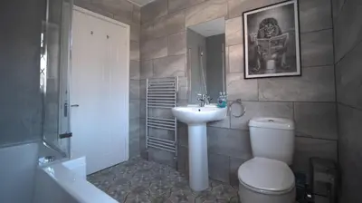 a bathroom with a sink and a toilet and a mirror at Spacious 3-Bed Home - Central Blackpool in Blackpool