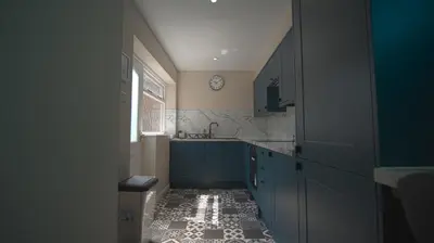 a kitchen with blue cabinets and a clock on the wall at Spacious 3-Bed Home - Central Blackpool in Blackpool