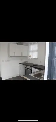 a kitchen with white cabinets and a stainless steel sink at Lane Stay in Liverpool