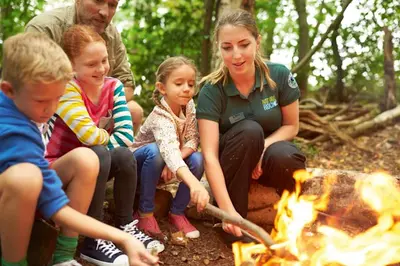 a group of people sitting around a fire at Miarlo Lodge Rydal Haven Lakeland in Flookburgh